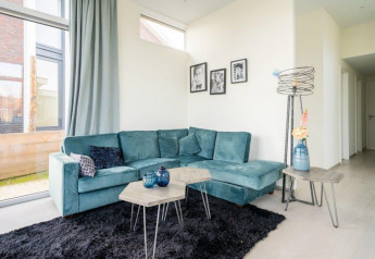 Moderne stue i Pavilion Waterfront 8, De Kraaijenbergse Plassen, Holland, med blå sofa og glasvinduer.