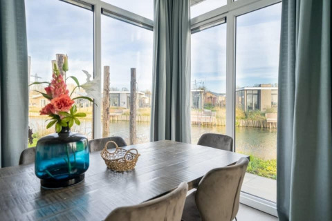 Modern dining area with large windows overlooking water at Pavilion Waterfront 8, De Kraaijenbergse Plassen.
