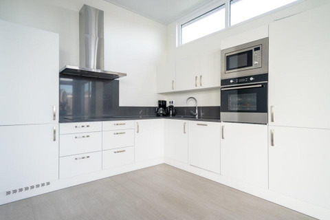 Moderne witte keuken in Pavilion Waterfront 8, De Kraaijenbergse Plassen, Nederland, met toestellen.