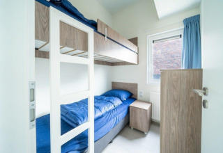 Habitación moderna de alojamiento con literas, muebles de madera y ropa de cama azul en Pavilion Waterfront 8, De Kraaijenbergse Plassen.