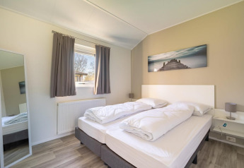 Dormitorio moderno en la cabaña Velthorst 4 en De Kraaijenbergse Plassen, Países Bajos, con cama doble.
