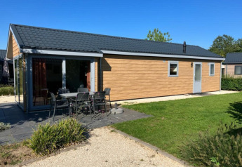 Velthorst 4 lodge aan De Kraaijenbergse Plassen in Nederland, met terras, tafel en stoelen buiten.