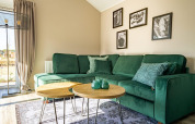 Moderne lodge woonkamer met een groene zetel, ronde houten tafels en zwart-wit foto's aan de muur.