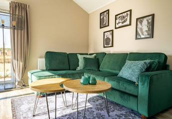 Moderne lodge woonkamer met een groene zetel, ronde houten tafels en zwart-wit foto's aan de muur.