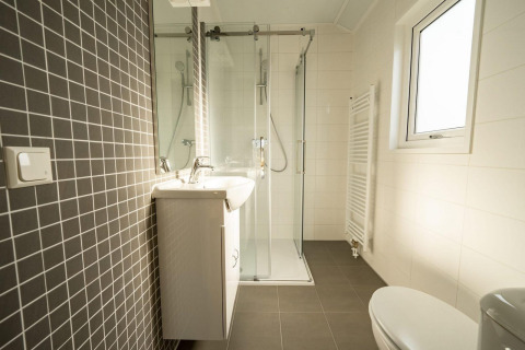 Modernes Bad in einer Lodge mit Doppellavabo, Dusche, Fenster und grauen Wandfliesen.