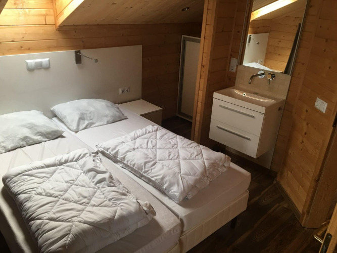Dormitorio de la lodge Boekhorst en Limburg, Países Bajos, con dos camas, paredes de madera y lavabo.