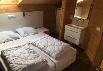 Dormitorio de la lodge Boekhorst en Limburg, Países Bajos, con dos camas, paredes de madera y lavabo.