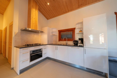 Cocina moderna en la cabaña Boekhorst de Limburg, Países Bajos, con gabinetes blancos y techo de madera