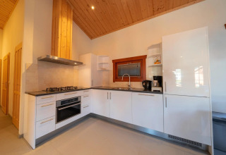 Cocina moderna en la cabaña Boekhorst de Limburg, Países Bajos, con gabinetes blancos y techo de madera