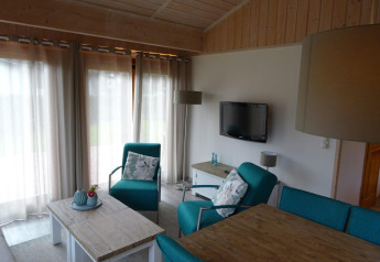 Accogliente soggiorno al lodge Boekhorst in Limburgo, Paesi Bassi, con poltrone turchesi e arredi in legno.
