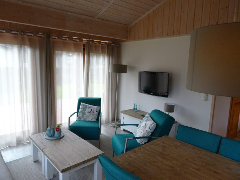 Acogedora sala en la lodge Boekhorst de Limburg, Países Bajos, con sillones turquesa y decoración de madera.