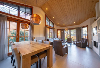 Salón luminoso y espacioso en la cabaña Boekhorst de Limburg, Países Bajos, con techo y ventanas grandes.