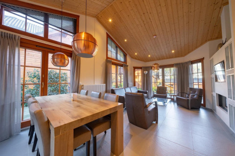 Salón luminoso y espacioso en la cabaña Boekhorst de Limburg, Países Bajos, con techo y ventanas grandes.