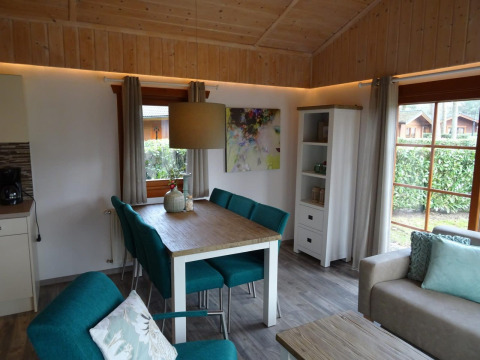 Vista interior de una acogedora cabaña Boekhorst en Limburg, Países Bajos, con comedor y sofá elegante.