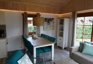 Vista interior de una acogedora cabaña Boekhorst en Limburg, Países Bajos, con comedor y sofá elegante.