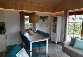 Vista interior de una acogedora cabaña Boekhorst en Limburg, Países Bajos, con comedor y sofá elegante.