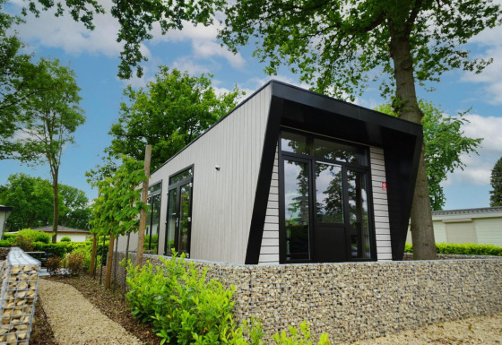 Moderne lodge Just Nature omgeven door bomen en natuur, gefotografeerd op een heldere lentedag