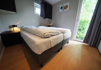 Moderne lodge soveværelse på Just Nature i Limburg, Holland med to senge, trægulv og udsigt til natur.