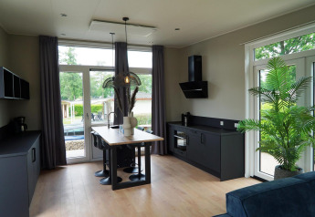 Moderne lodgekeuken bij Just Nature in Limburg, Nederland, met grote ramen en stijlvol donker meubilair.