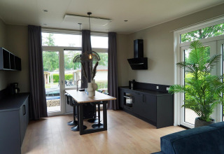 Moderne lodgekeuken bij Just Nature in Limburg, Nederland, met grote ramen en stijlvol donker meubilair.