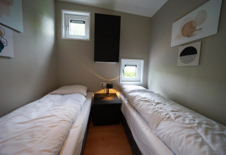 Habitación moderna de una cabaña con dos camas individuales y ventanillas en Just Nature, Limburg.