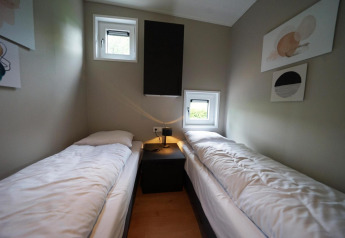 Moderne lodgeværelse med to enkeltsenge, vinduer og minimalistisk dekoration på Just Nature, Limburg.