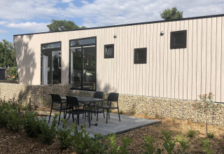 Modern lodge Just Nature a Limburg, Paesi Bassi, con area patio, tavolo e sedie nel giardino.