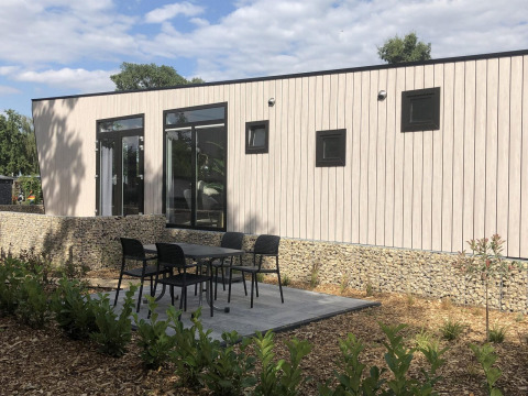 Modern lodge Just Nature a Limburg, Paesi Bassi, con area patio, tavolo e sedie nel giardino.