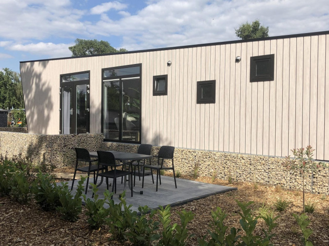 Lodge moderno Just Nature en Limburg, Países Bajos, con terraza al aire libre, mesa y sillas en el jardín.