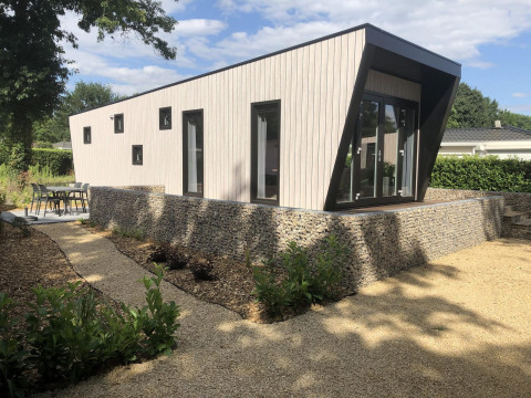 Lodge moderno Just Nature en Limburg, Países Bajos, diseño contemporáneo, jardín y muro de piedra.