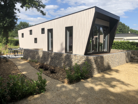 Moderne Lodge Just Nature Light in Limburg, Niederlande, mit stilvollen Steinwänden und gepflegtem Garten.