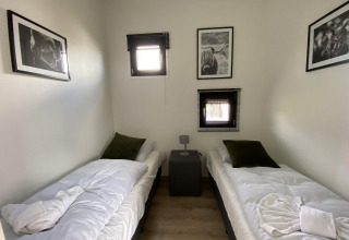 Habitación con dos camas individuales, fotos de animales en las paredes, ventanas pequeñas en Limburg, Países Bajos.