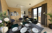 Interni moderni della lodge Just Nature Light a Limburg, Paesi Bassi, con sala da pranzo e ampie finestre.