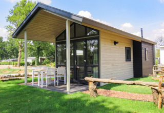 Tiny House moderno en Limburg, Países Bajos, con terraza cubierta, comedor exterior y césped verde.