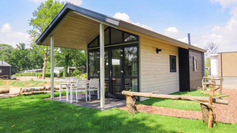 Tiny House moderno en Limburg, Países Bajos, con terraza cubierta, comedor exterior y césped verde.