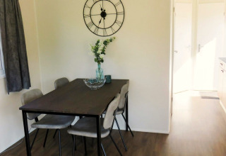 Essbereich in der Berkel 4 Lodge am Zuiderzee, Niederlande, mit Tisch, Stühlen und Uhr an der Wand.