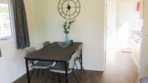 Essbereich in der Berkel 4 Lodge am Zuiderzee, Niederlande, mit Tisch, Stühlen und Uhr an der Wand.