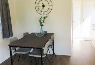 Essbereich in der Berkel 4 Lodge am Zuiderzee, Niederlande, mit Tisch, Stühlen und Uhr an der Wand.