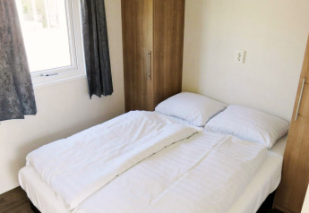 Camera luminosa con letto matrimoniale, lenzuola bianche e armadi, Berkel 4 lodge, Zuiderzee, Paesi Bassi.