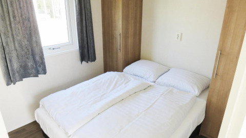Camera luminosa con letto matrimoniale, lenzuola bianche e armadi, Berkel 4 lodge, Zuiderzee, Paesi Bassi.