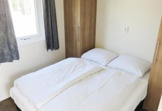 Helles Schlafzimmer mit Doppelbett, weißen Bettwaren und Kleiderschränken, Berkel 4 Lodge, Zuiderzee, Niederlande.
