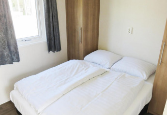 Lichte slaapkamer met tweepersoonsbed, witte lakens en kasten, Berkel 4 lodge, Zuiderzee, Nederland.