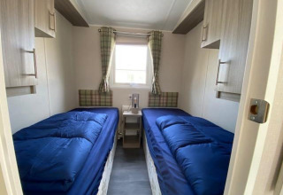Habitación con dos camas individuales, edredones azules, ventana y armarios en Berkel 4, Zuiderzee, Países Bajos.