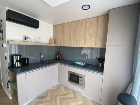 Moderne kitchenette in Domus 4 aan Zuiderzee, Nederland, met hout- en grijstinten en ingebouwde apparatuur.