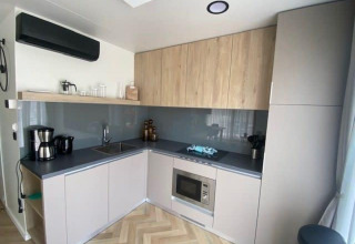 Angolo cottura moderno a Domus 4 presso Zuiderzee, nei Paesi Bassi, con mobili grigi e in legno e elettrodomestici.
