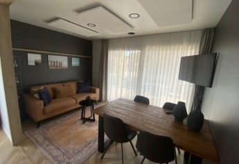 Moderne leefruimte met bruine zetel, houten eettafel en tv in Domus 4 bij Zuiderzee, Nederland.