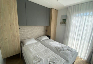 Moderne slaapkamer in Domus 4-lodge bij Zuiderzee, Nederland, met twee bedden en veel lichtinval.