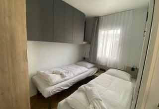 Twee aparte bedden in een compacte, lichte kamer in Domus 4 lodge aan de Zuiderzee in Nederland.