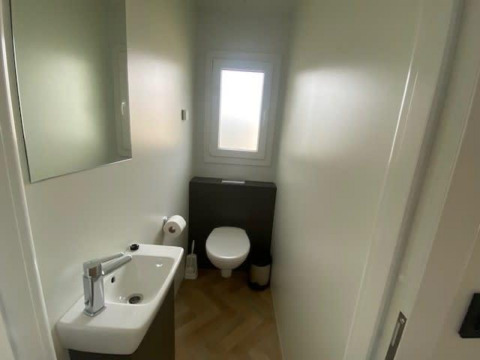 Moderne, compacte badkamer in Domus 4 bij Zuiderzee, Nederland, met toilet, wastafel en raam.