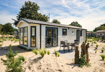 Moderne Berkel 6 lodge met terras en tuinmeubilair, omringd door zand en groen in een vakantiepark.